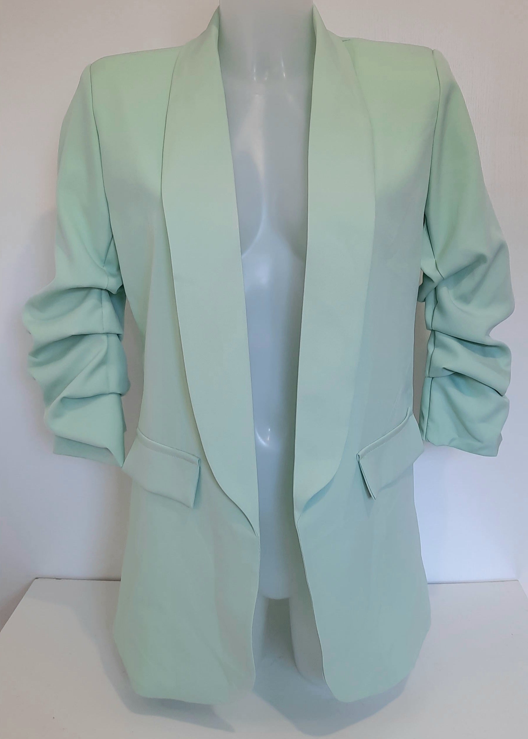 Veste tailleur pour femme en tissu fluide vert d’eau, coupe droite avec manches 3/4 froncées, poches à rabat décoratives et col élégant, idéale pour un look tendance, frais et féminin – modèle Timalya prêt-à-porter.